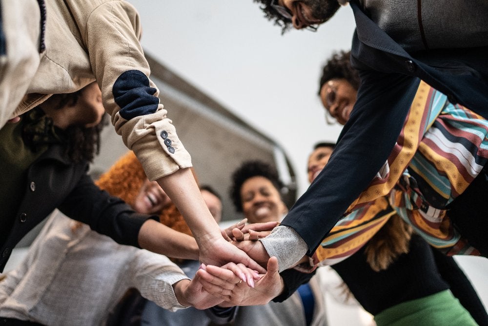 Team joining hands in unity, symbolizing collaboration for creative growth